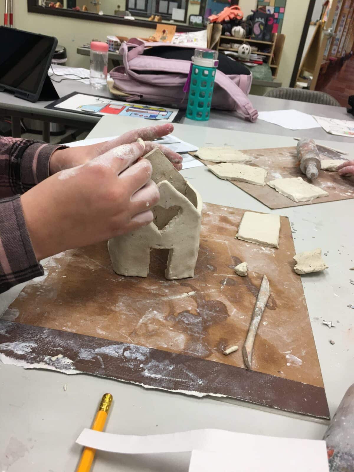 A person is making a clay house