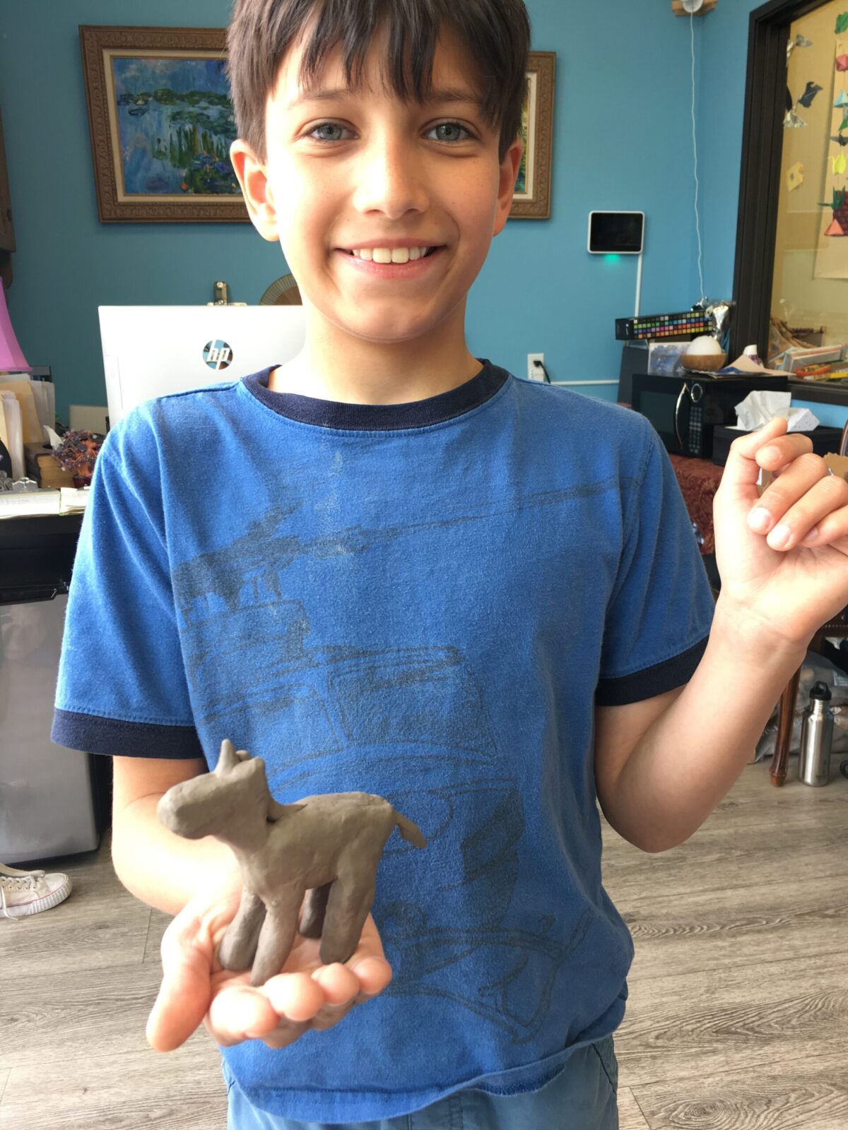 A kid proudly showing his horse made of clay