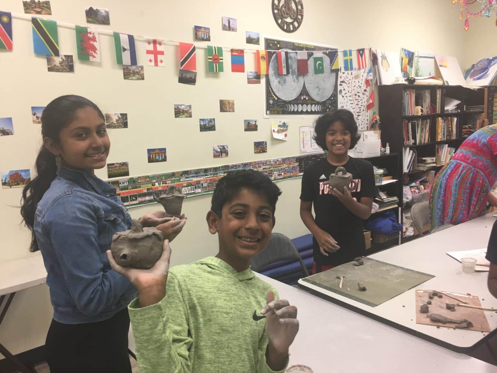 Three kids that are happy showing their clay crafts